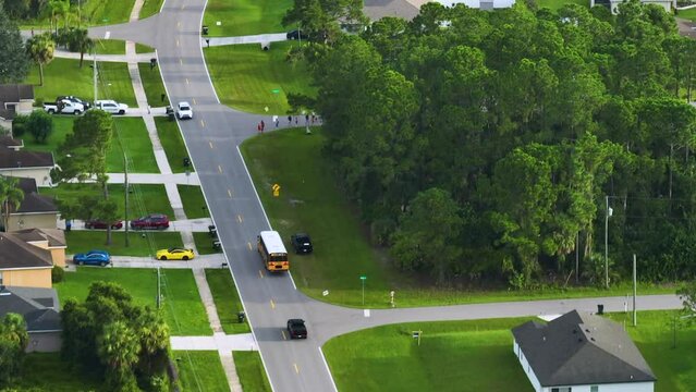 Aerial view of american yellow school bus picking up children at bus stop for their lessongs in early morning. Public transportation in the USA