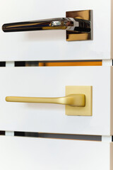 A stand of doorknobs in a store. Metal door handles of golden and bronze color.