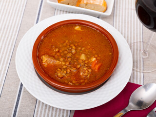 Stewed lentils with sausages, carrot, tomato and onion in bowl, popular spanish dish Lentils a la Riojana