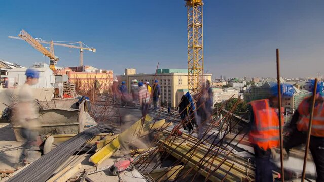 Steel bar rebar metal framework reinforcement for concrete at construction site with cranes timelapse. Metal works on a roof of new building in progress with many workers in uniform