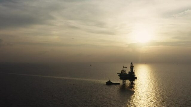 Jack up drilling rig and production platform in the middle of the ocean at sunrise time
