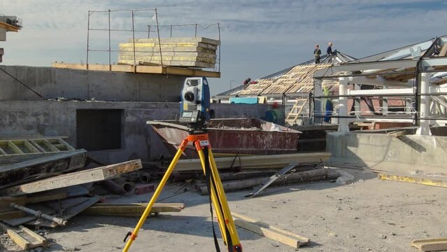Construction worker using theodolite surveying optical instrument timelapse. Builders and carpenters in uniform working on the roof. Measuring angles in horizontal and vertical planes on construction