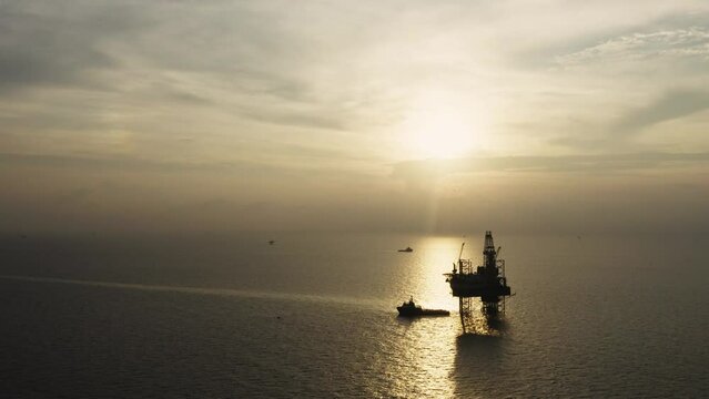Jack up drilling rig and production platform in the middle of the ocean at sunrise time
