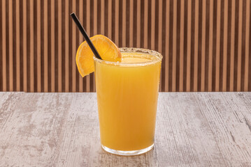 A delicious and refreshing glass of fresh orange juice with a straw, sugar and a slice of decoration