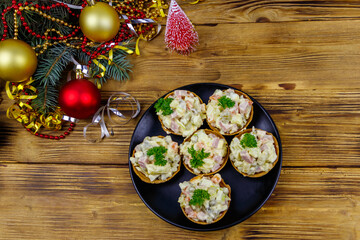Traditional Russian festive salad Olivier in tartlets and Christmas decorations on wooden table. Top view