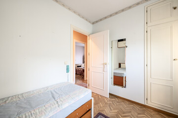 A bedroom with antique white wooden furniture, a single bed, a mirror on the wall and a built-in wardrobe