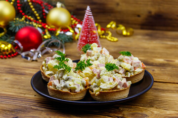 Traditional Russian festive salad Olivier in tartlets and Christmas decorations on wooden table