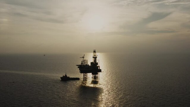 Jack up drilling rig and production platform in the middle of the ocean at sunrise time
