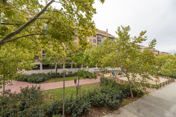 Landscaped areas of an urbanization with trees and a fenced children's play park