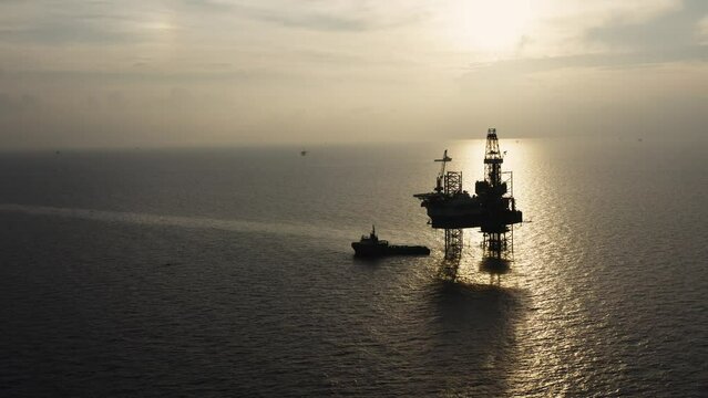 Jack up drilling rig and production platform in the middle of the ocean at sunrise time
