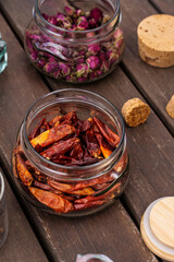 Glass jars full of dried hot chili peppers and other seasonings