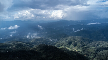 Aerial view of tropical forest with mist in the morning. Top view from drone of beautiful mountain tropical forest during winter in Thailand. Natural landscape background.