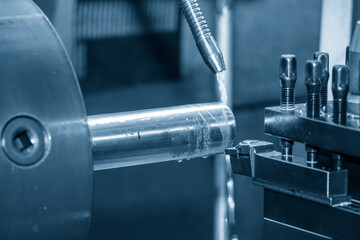 The lathe machine cutting the metal shaft parts with coolant method.
