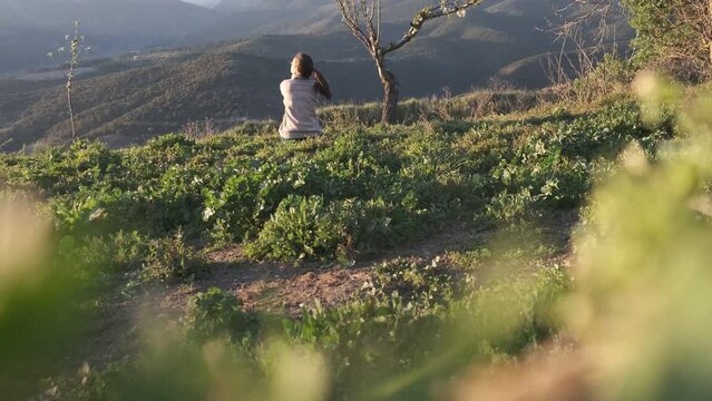 4kk v&iacute;deo. Slow motion chica cauc&aacute;sica sentada en la hierba en el monte durante el verano