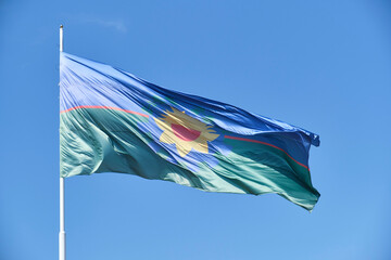 Flag of the Province of Buenos Aires waving in the wind over a clear sky.