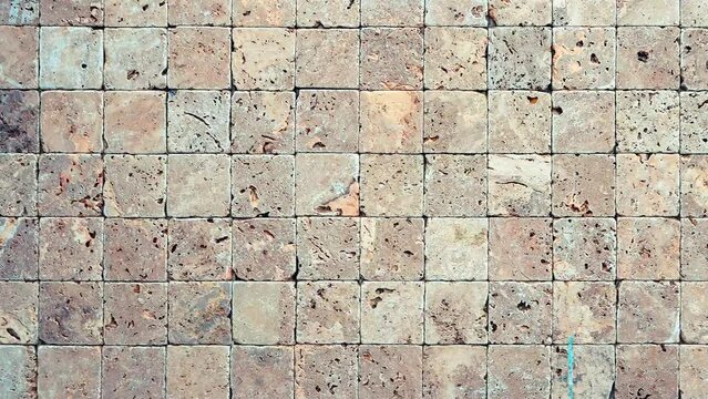 Square stones surface background loop. Travertine masonry tiles cladding wall texture.