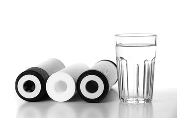 Banner of three of cartridges for water filter with clear fresh glass of water isolated on white...