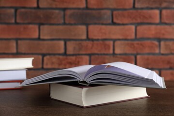 Hardcover books on wooden table near brick wall