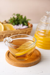 Cup of delicious tea with lemon and honey on white table