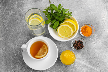 Cup with delicious immunity boosting tea and ingredients on grey table, above view