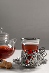 Glass of traditional Turkish tea in vintage holder with sugar on white table