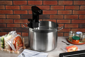 Thermal immersion circulator in pot and ingredients on beige table. Vacuum packing for sous vide...