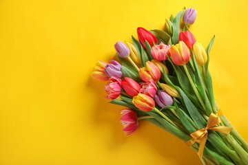 Bunch of beautiful tulips on yellow background, top view. Space for text