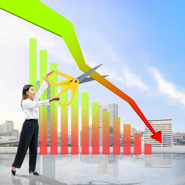 Asian businesswoman holding scissors to cut decrease arrow on the graph