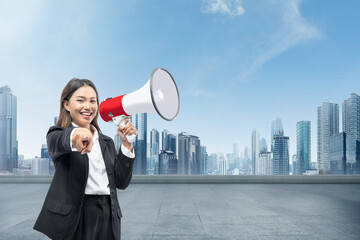 Asian businesswoman talking on a megaphone and pointing to you