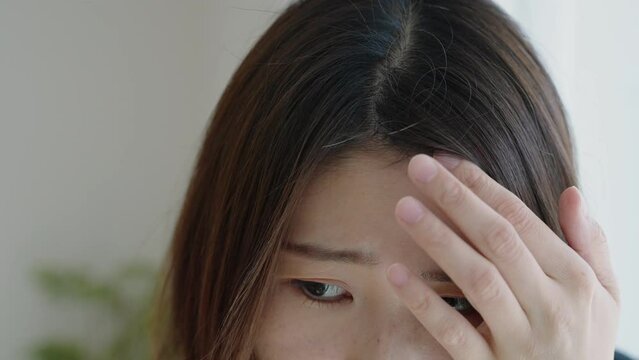髪の毛の生え際をチェックする女性（プリン髪・ハゲ）