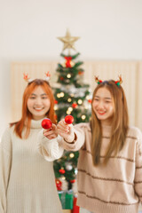 Christmas concept, Two women wears reindeer horns and holding red christmas ball for decoration