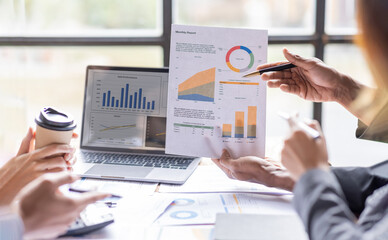 Group of confident business people point to graphs and charts to analyze market data, balance sheet, account, net profit to plan new sales strategies to increase production capacity.