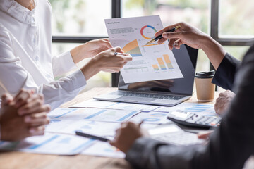 Group of confident business people point to graphs and charts to analyze market data, balance sheet, account, net profit to plan new sales strategies to increase production capacity. - obrazy, fototapety, plakaty