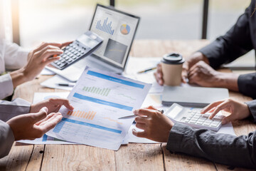 Group of confident business people point to graphs and charts to analyze market data, balance sheet, account, net profit to plan new sales strategies to increase production capacity.