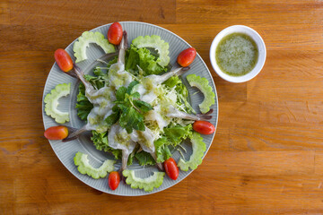 Shrimp in Spicy Fish Sauce on ceramic plate decorated with bitter gourd and tomato. Seafood with spicy sauce on wooden table. Top View