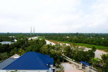 aerial view of Villa house in the middle of the garden with blue tile roof and the river at Mekong river delta VietNam countryside, Thai house building style. 