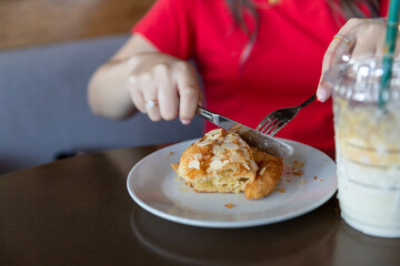 A woman cutting bread with a knife and drinking milk for breakfast