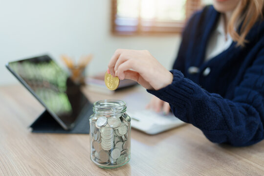 Cryptocurrency savings plan, Asian young woman saving digital coins into a piggy bank - Powered by Adobe