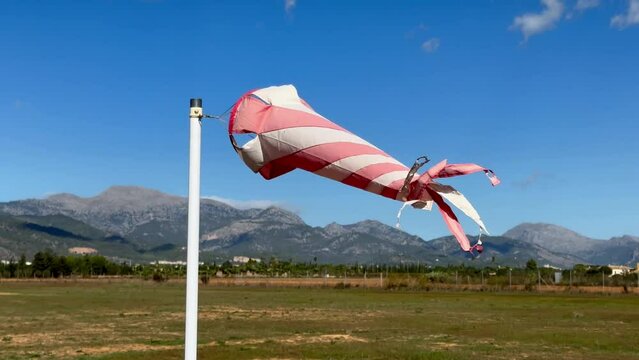 White and orange windsock spinning on strong wing on beautiful sunny day
