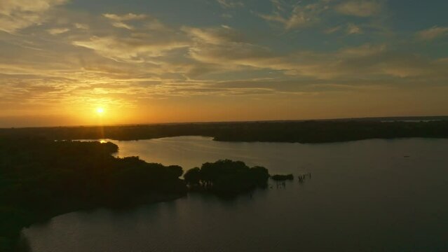  HQ Aerial footage - Drone moving aside between trees at the sunset with a boat right side