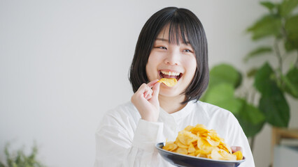 ポテトチップスを食べる女性（不健康・ダイエット）..