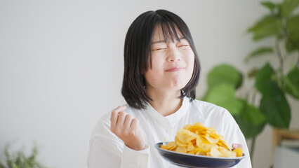 ポテトチップスを食べる女性（不健康・ダイエット）..