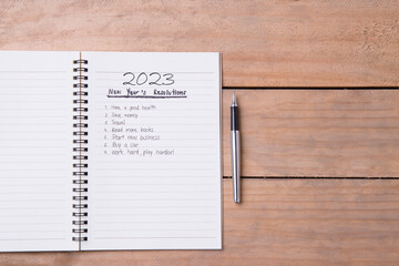 List of New Year's resolution on notepad, vintage style on wood with space for layout.