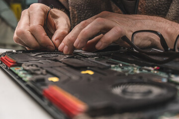 computer repair technician removes laptop cooling system from case for maintenance and cleaning....
