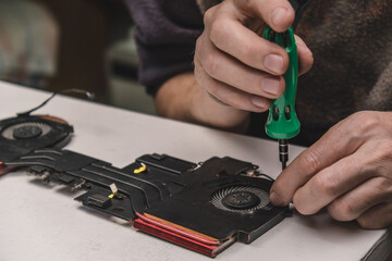 updating computer components. fixing the fan in the laptop cooling system with screws and screwdriver. laptop maintenance. concept of computer equipment, repair and technology. close up.