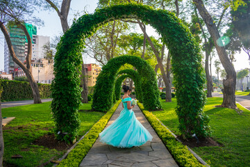 Beautiful young woman dressed in princess costume in the middle of arch of plants