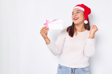 Joyful young Asian woman 20s in a Santa Claus hat holding a gift certificate coupon voucher card...