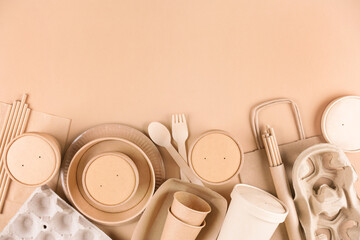Paper utensils, cups, plates, drinking straws, egg boxes, bamboo cutlery set and food containers over light brown background with copy space. Food delivery service, sustainable paper packaging