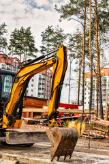 Close-up mini excavator during the construction of a modern residential complex. Miniature...