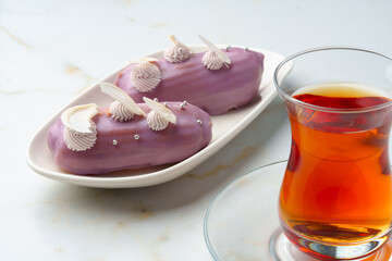 Two eclair cakes with violet frosting on white plate